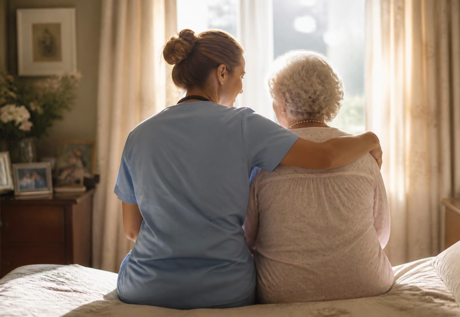 Hospice nurse comforting an elderly woman at home